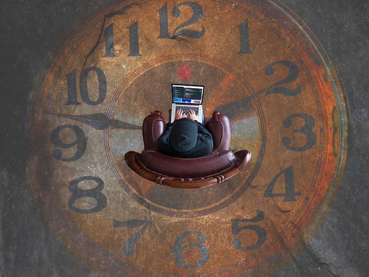 A birds eye view of a person working on a laptop in a chair which is sitting on the image of a clock - Katie Stone, Education Business Services